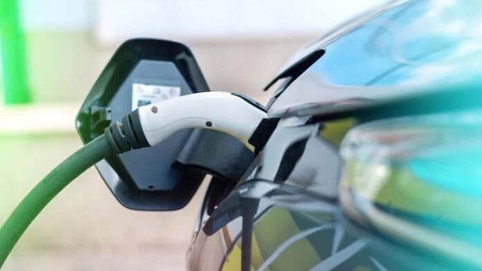 Imagem mostra carro elétrico sendo carregado.