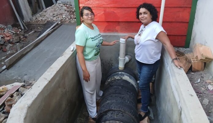 Duas mulheres em obra de construção de fossa natural