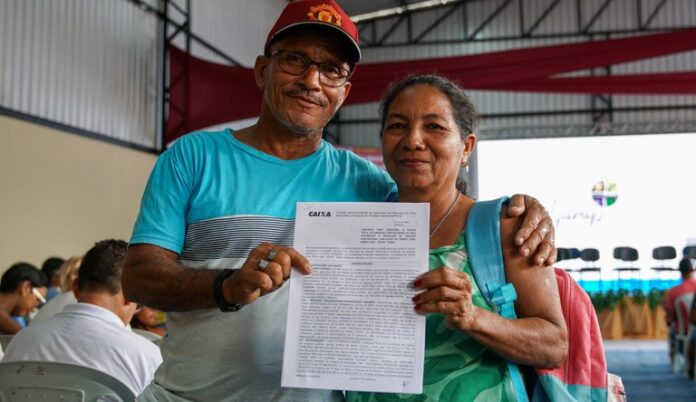 Na imagem casal com contrato da casa própria